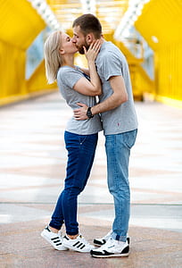 kissing couple in gray shirts with denim jeans and white-and-black shoes during daytime thumbnail