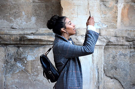 woman holding her phone near brown wall thumbnail