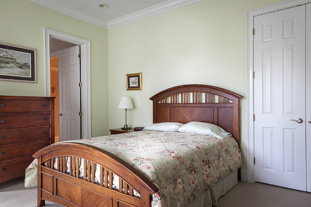 brown wooden panel bed and gray and pink floral bedspread beside white wooden 6-panel door thumbnail