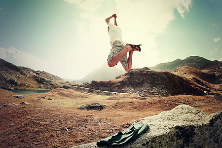 man in white shirt and gray shorts jumping over the field during daytime thumbnail