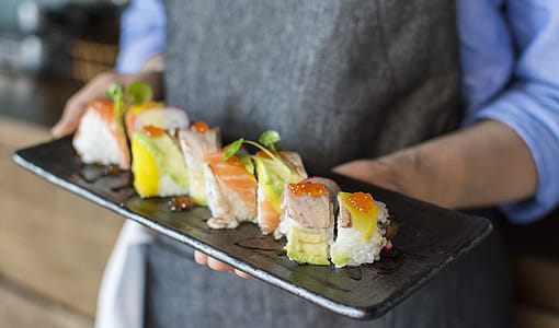 Person Holding Sushi on Black Plate thumbnail