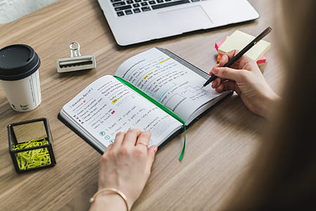 person holding black pen and white notebook thumbnail