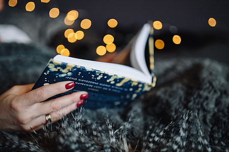 Young woman at home reading Hygge book and drinking thumbnail