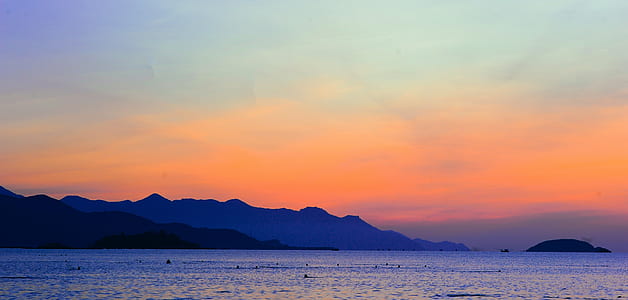 Silhouette of Mountain Beside Ocean during Orange Sunset thumbnail