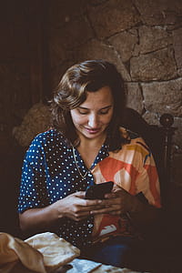 Woman Sitting on Wooden Chair While Using Smartphone thumbnail