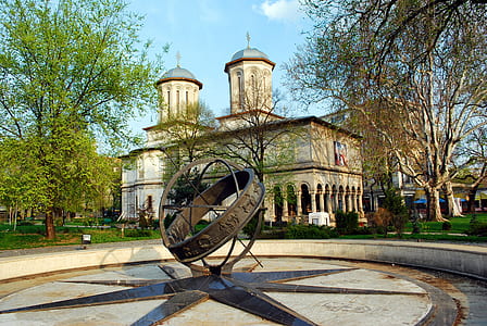 brown building behind brown metal fountain during daytime thumbnail