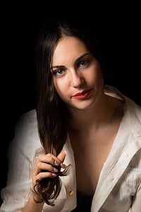 woman wearing white button-up top holding her hair thumbnail