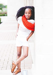 photo of girl smiling leaning on white concrete wall thumbnail