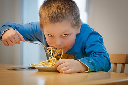 boy in blue sweatshirt eating pasta on brown wooden table during daytime thumbnail