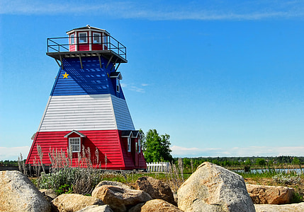 multicolored lighthouse near brown rocks thumbnail