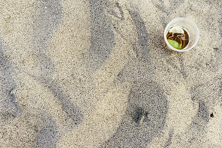 flat lay photography of clear disposable cup on gray sand thumbnail