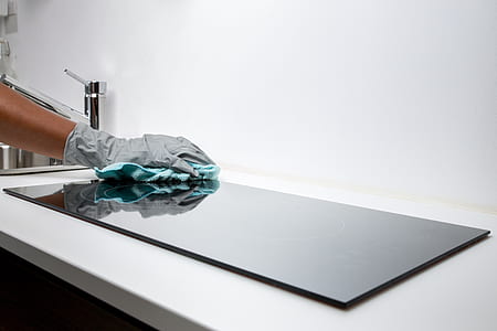 person wearing gray glove holding blue textile on glass thumbnail