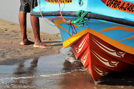 person standing near blue and orange boat thumbnail
