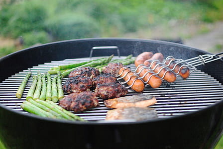 person grilling meats, vegetables, and hotdogs thumbnail