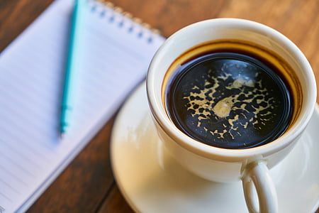 white ceramic teacup with tea near notepad thumbnail