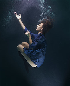 woman wearing blue elbow sleeve mini dress raising her right hand under water thumbnail