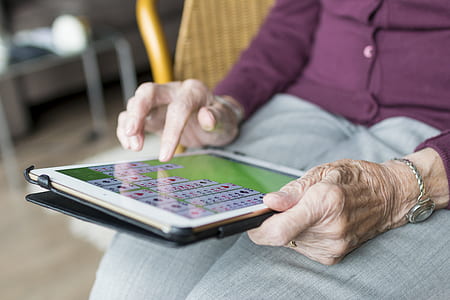 person with purple button-up jacket using white iPad close-up photo thumbnail
