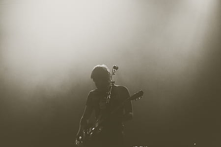 man playing guitar in sepia photography thumbnail