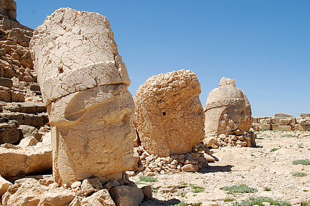 three stone head statues on brown field thumbnail