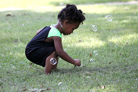 girl playing bubbles on green grass field thumbnail