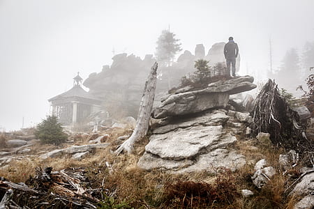 man standing on rock cliff surrounded by fogs thumbnail