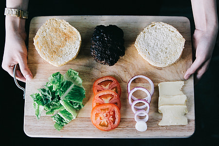 photo of person holding chopping board with sliced bread, tomato, onions, vegetable, and butter thumbnail