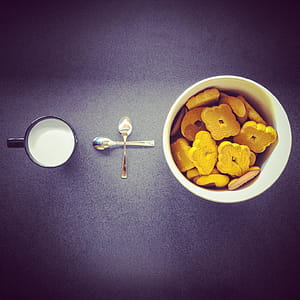 Crackers in Round White Ceramic Cup Near Two Stainless Steel Spoons and Black Ceramic Mug thumbnail