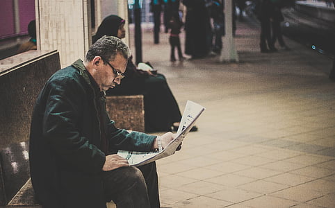 man holding newspaper on bench thumbnail