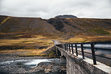 A bridge over a fresh water stream surrounded by moss grown mountains thumbnail