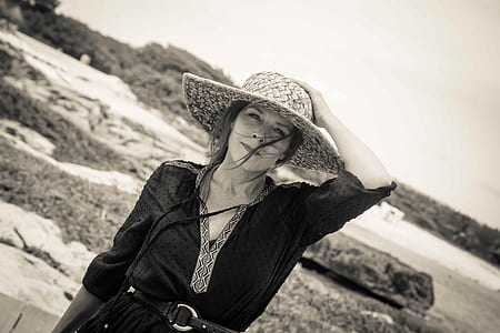 grayscale photo of woman holding her hat thumbnail