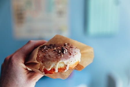 Fresh doughnut glazed with icing held in a hand thumbnail