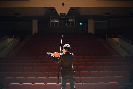 man wearing black long-sleeved shirt playing violin in front of chairs thumbnail
