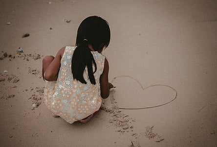 girl wearing beige floral dress standing on wet sand thumbnail