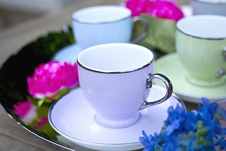 white and gray ceramic coffee cup on saucer beside pink and blue flowers thumbnail