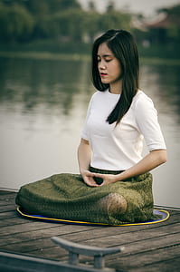 woman wearing white shirt and green skirt doing concentration near body of water during daytime thumbnail
