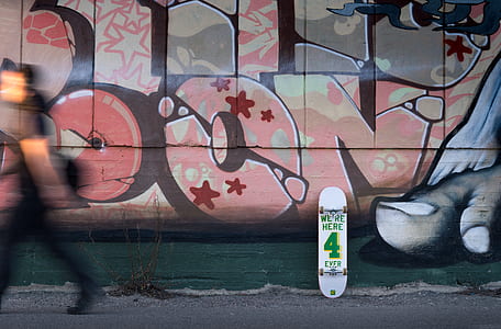 white and green skateboard leaned on wall with graffiti thumbnail