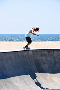man riding skateboard on gray concrete ramp near body of water thumbnail