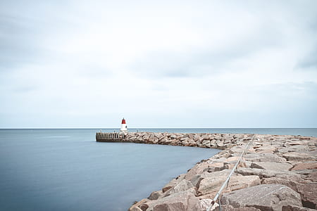 white and red lighthouse on rocks thumbnail