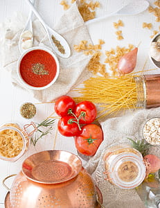 flat lay photography of uncooked pasta, tomatoes, colander, and jar thumbnail