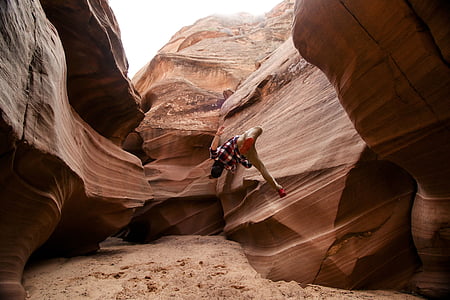 person jump inside brown cave at daytime thumbnail