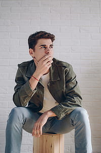 Man Wearing A Jacket Sitting On Brown Wooden Crate thumbnail