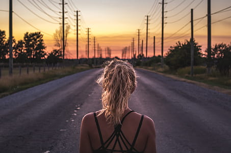 selective focus photo of woman wearing black spaghetti strap top standing in the middle of concrete road at golden time thumbnail