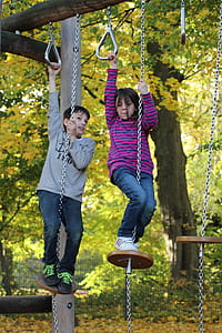 girl and boy playing under green tree thumbnail