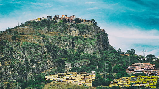 buildings near mountain covered with trees thumbnail