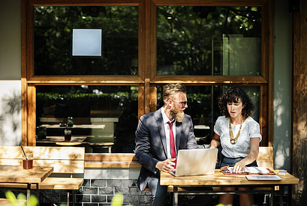 man and woman siting in front of brown wooden table during daytime thumbnail