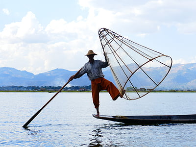 man standing in front of boat holding fishing basket thumbnail