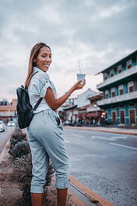 Woman in Blue Top Holding White Paper Cup Outdoors thumbnail
