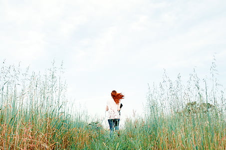 woman standing on grass field under white clouds at daytime thumbnail