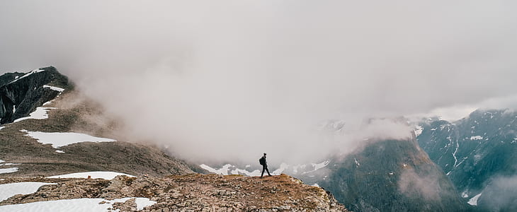 person standing on mountains at daytime thumbnail