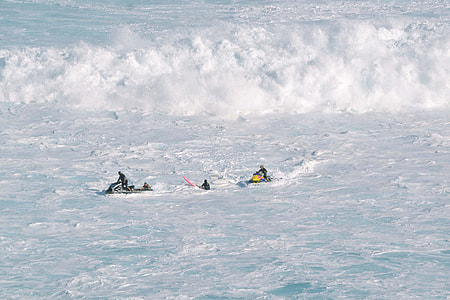 group of people riding personal watercraft near high waves during daytime thumbnail